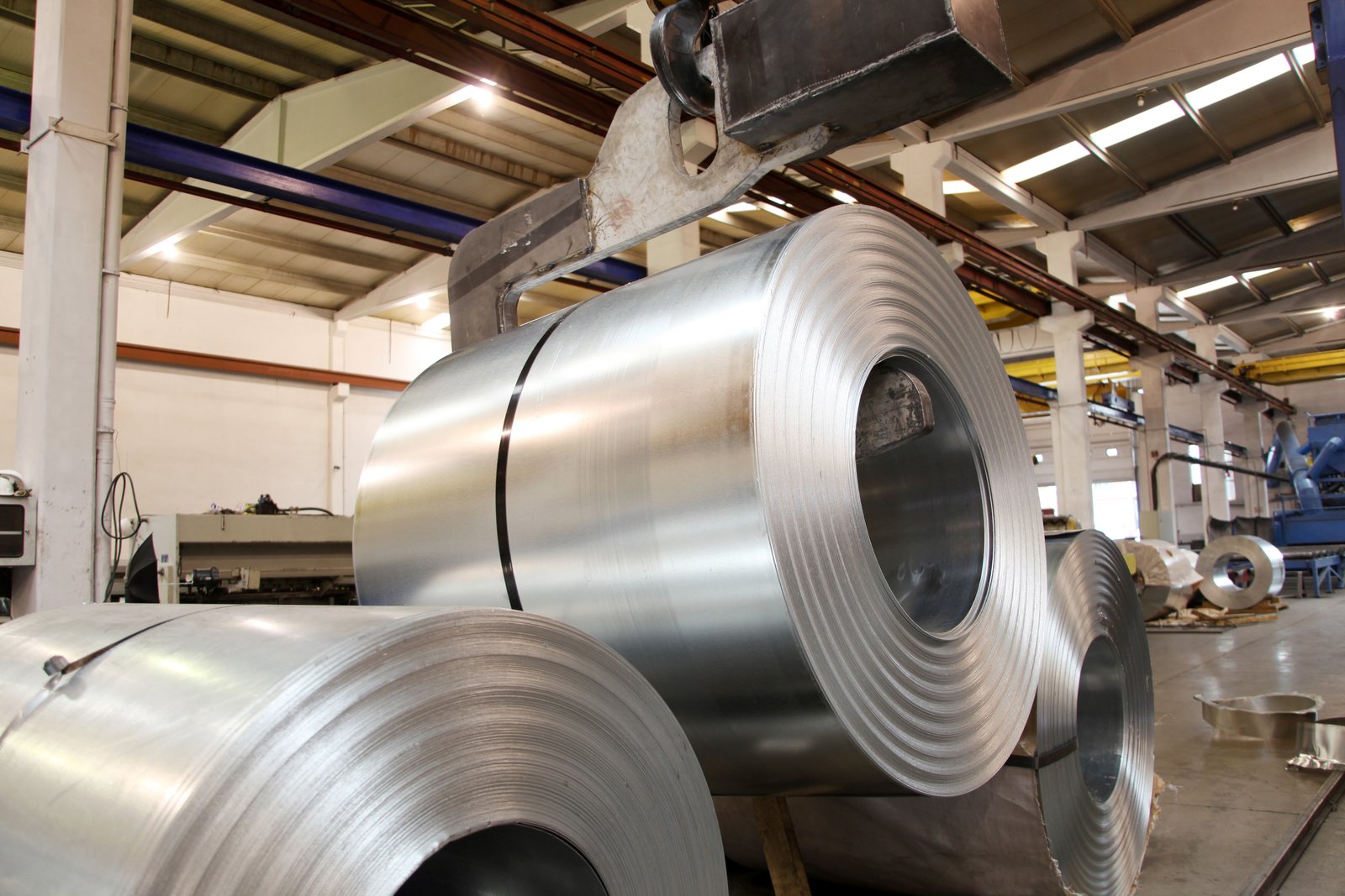Overhead crane lifting bright annealed stainless steel coil, demonstrating AKS’s robust handling system in production facilities.