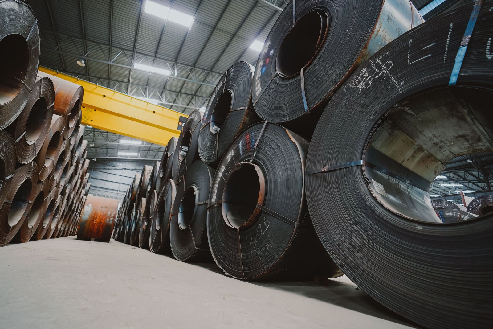 Warehouse operator inspecting stainless steel coil stock inventory for production planning and material tracking at AKS facility
