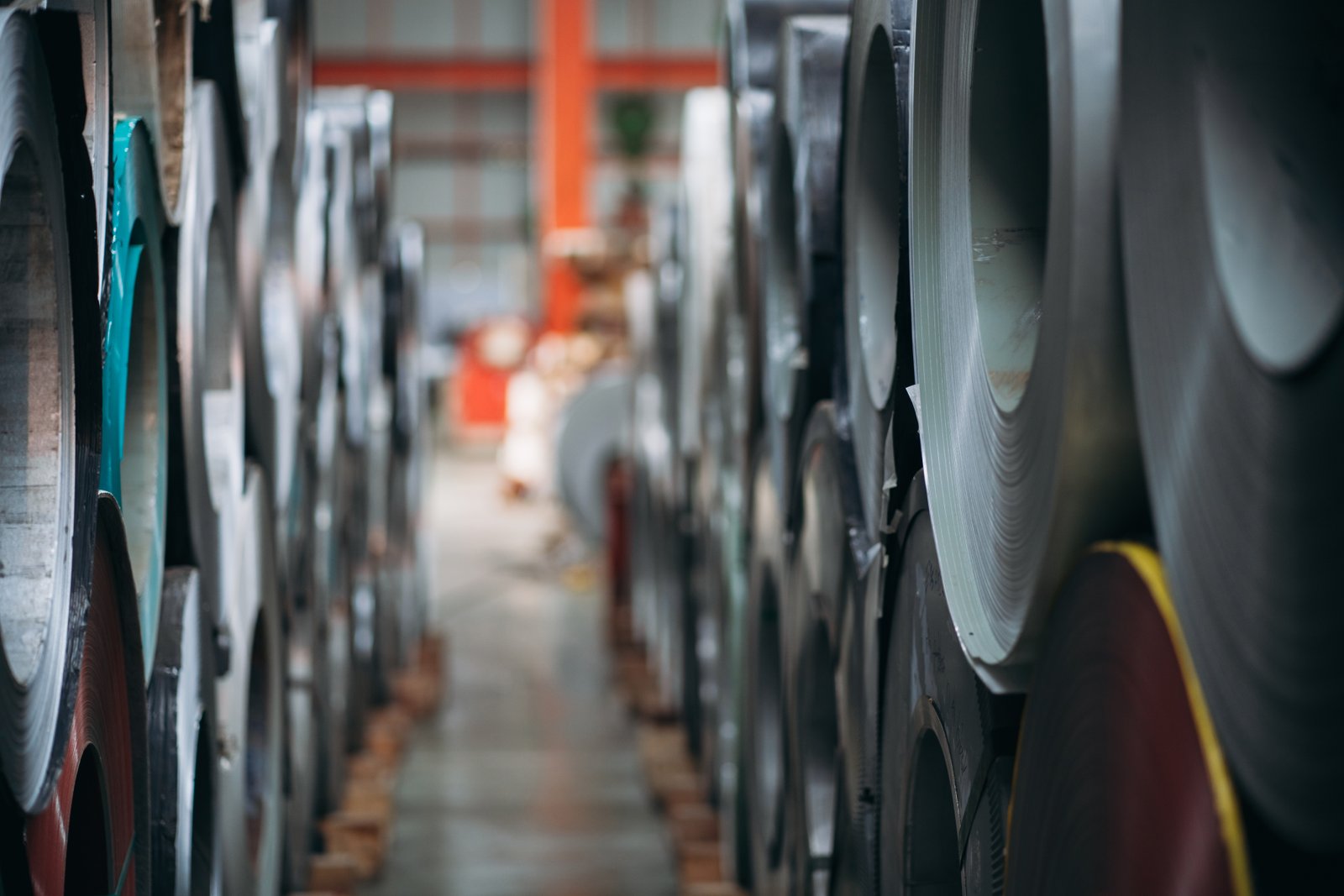 Aisle view of vertically stacked stainless steel coils in raw material warehouse for precision heat treatment preparation