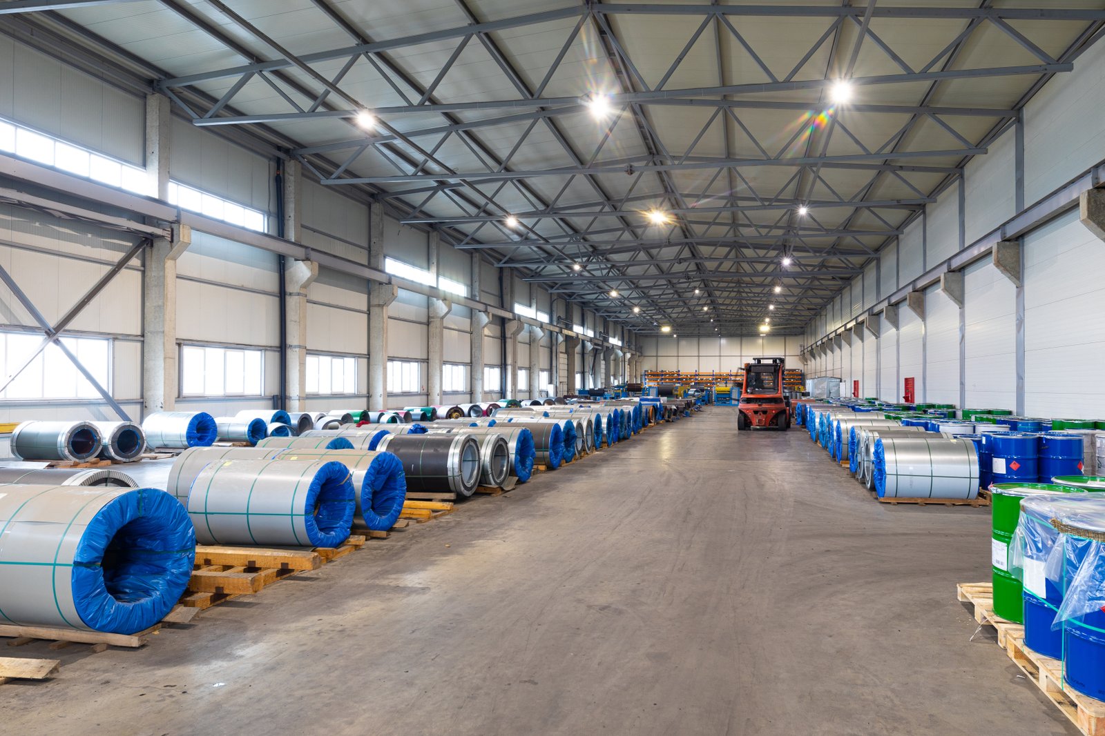 Stainless steel coils with protective wrap stored on pallets inside bright, clean AKS warehouse