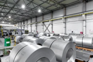 Interior view of a steel processing facility showing large rolls of steel ready for heat treatment, highlighting industria...