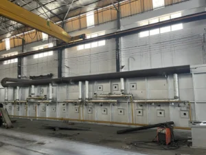 Large bright annealing furnace in a factory setting with overhead crane, designed for heat treatment of stainless steel st...