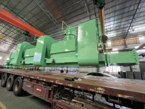 Large green industrial heat treatment equipment being transported in a factory setting